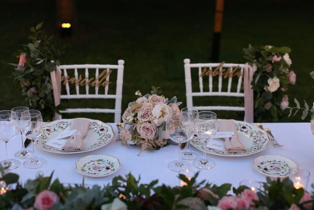 Un tavolo con sopra piatti, bicchieri e fiori.