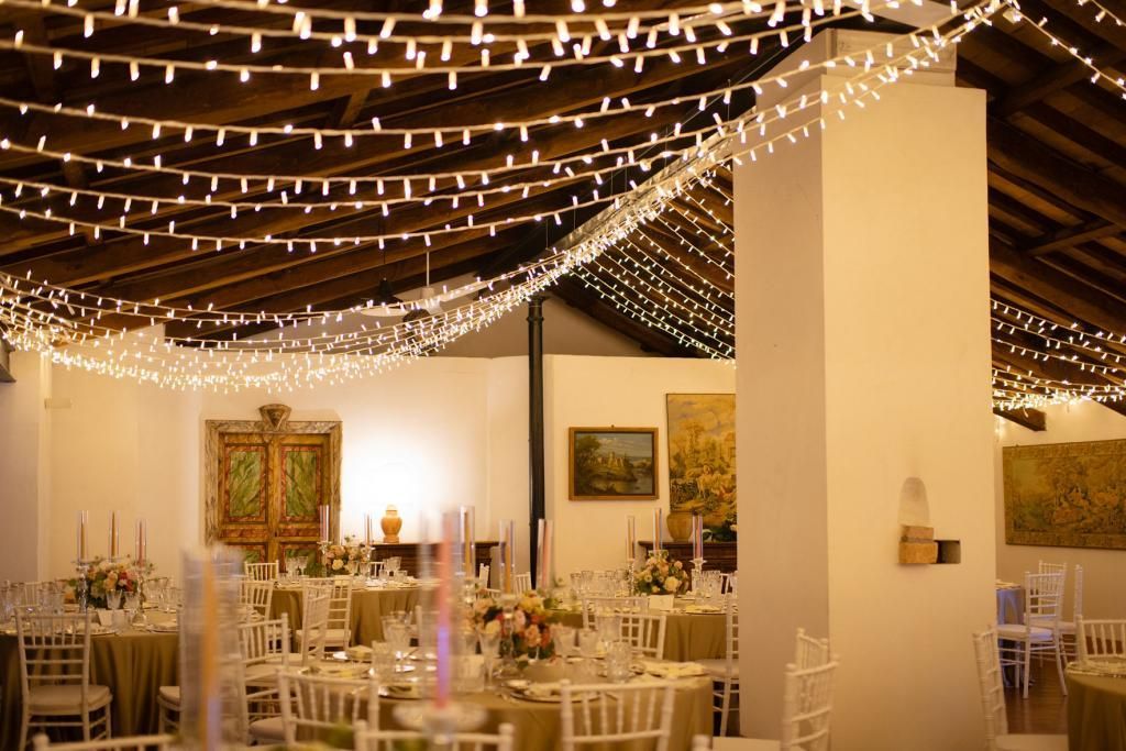 Una stanza con tavoli e sedie e un filo di luci che pende dal soffitto.