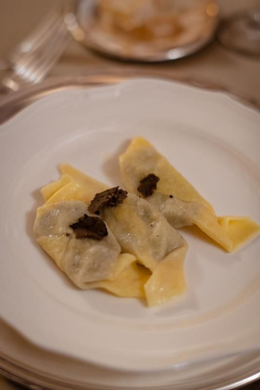 Su un tavolo un piatto bianco sormontato da due ravioli al tartufo.