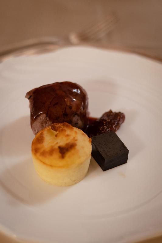 Un piatto bianco sormontato da una fetta di torta e da un pezzo di cioccolato.