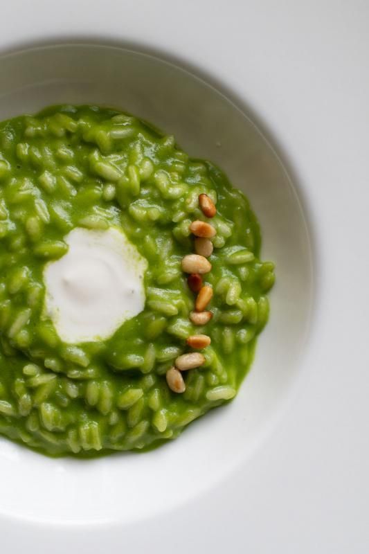 Un primo piano di una ciotola di riso verde con pinoli e panna acida.