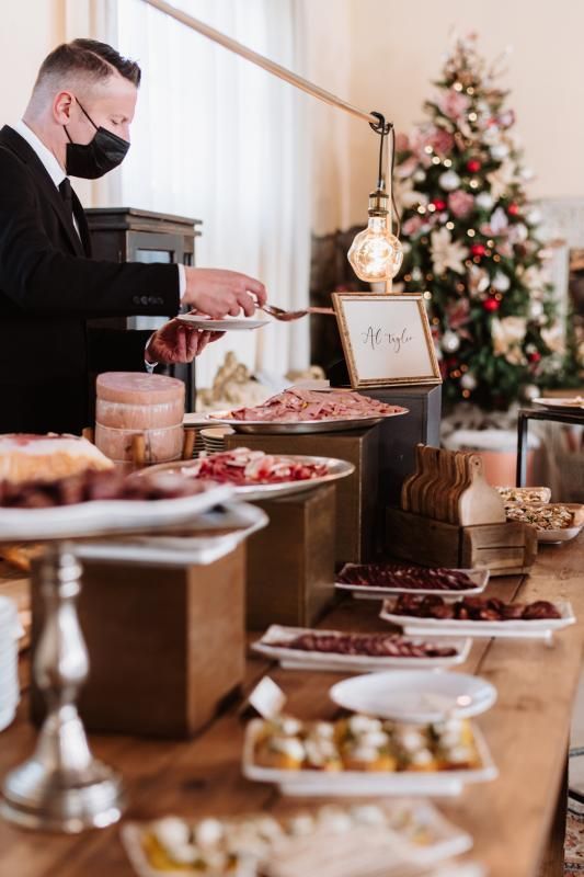 Un uomo che indossa una maschera serve il cibo al tavolo del buffet.