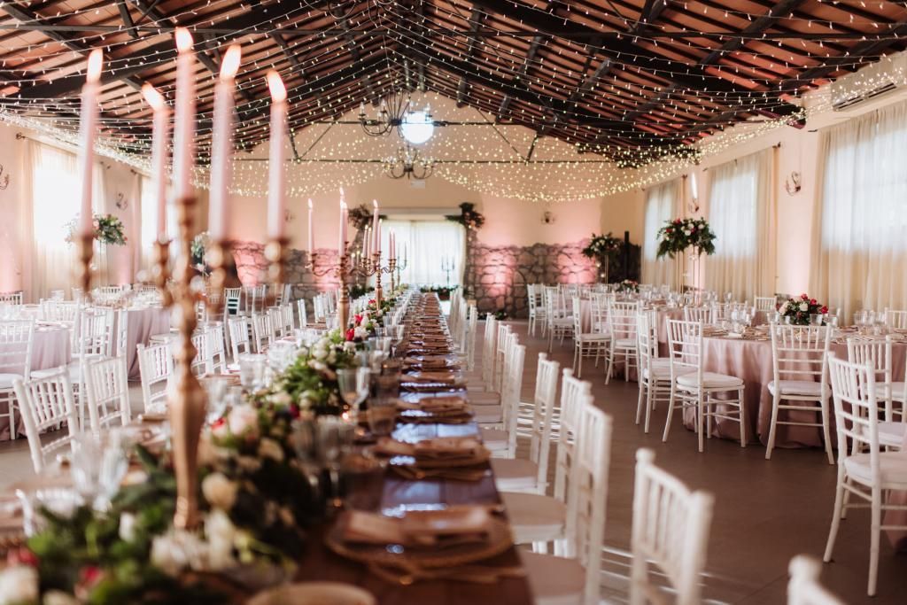 Un lungo tavolo con candele e fiori sopra in una grande stanza.