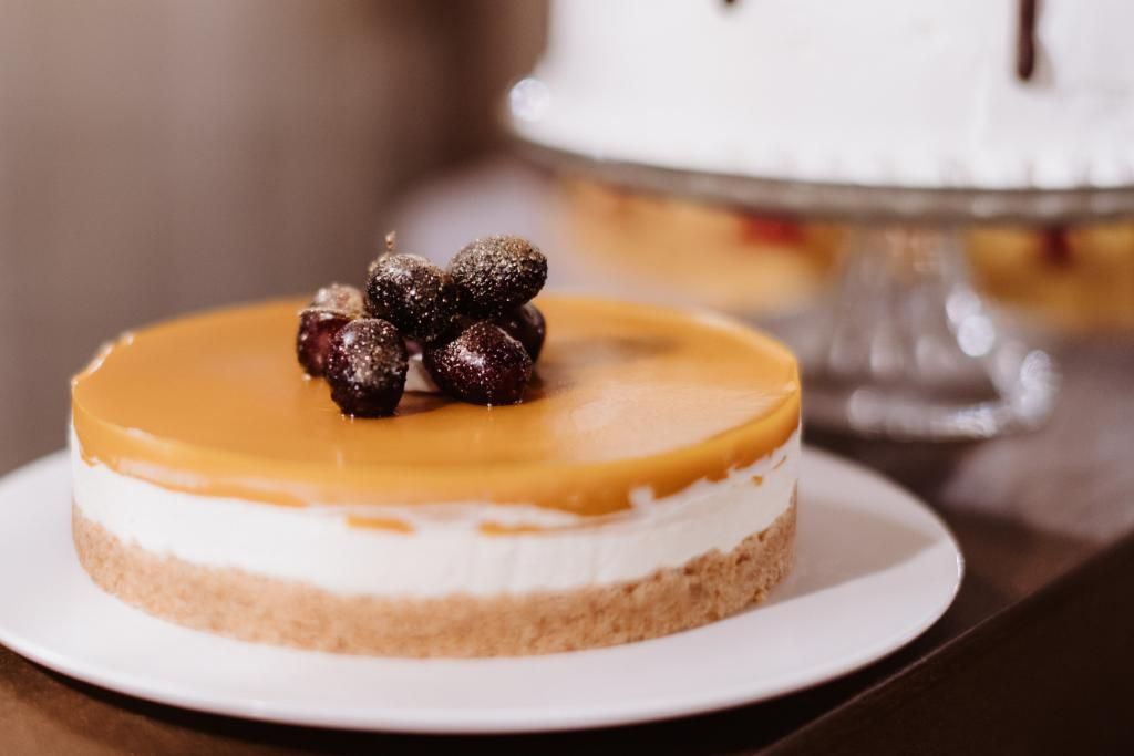 Una cheesecake con frutti di bosco in cima è su un piatto bianco su un tavolo.