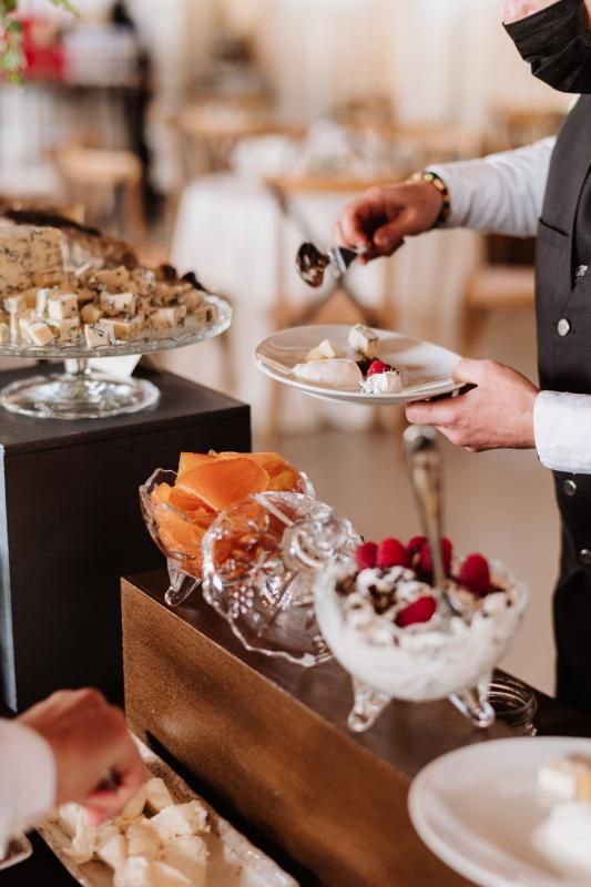 Un uomo che indossa una maschera serve cibo a un tavolo da buffet.