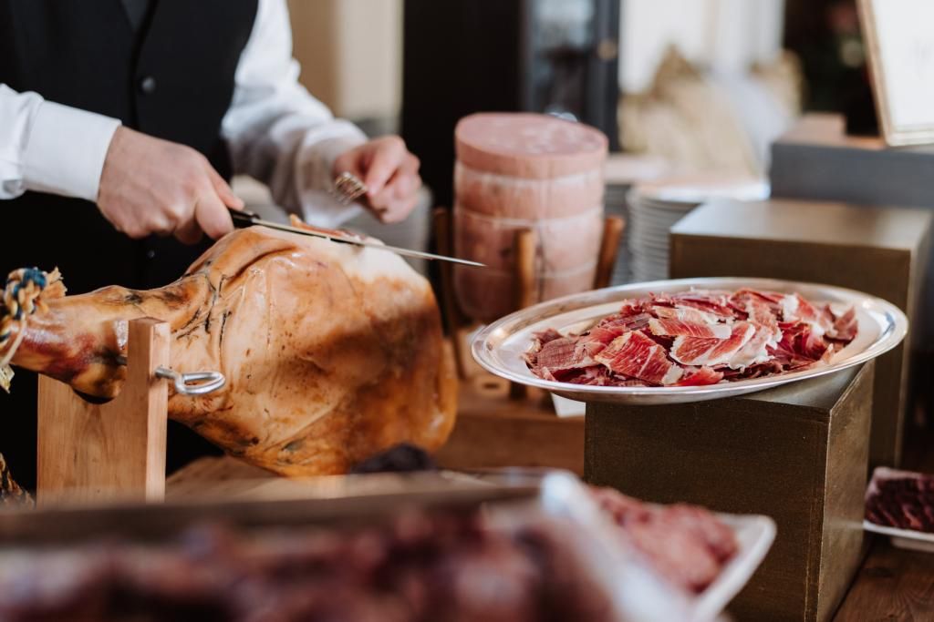 Un uomo sta tagliando un pezzo di prosciutto su un tagliere.