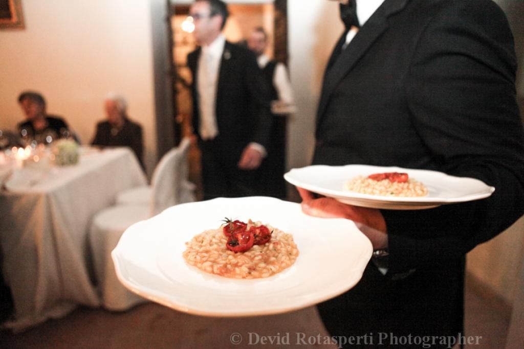 Un uomo in giacca e cravatta porta due piatti di cibo
