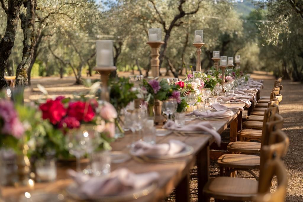 Una lunga tavola apparecchiata per un ricevimento di nozze in mezzo ad un bosco.