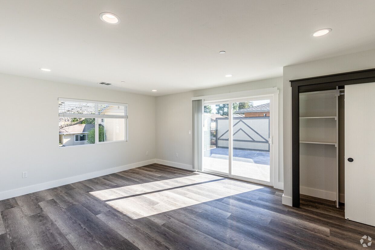 An empty living room with hardwood floors and sliding glass doors.