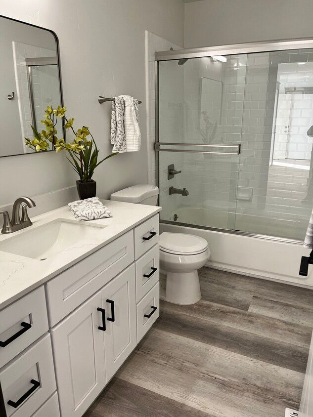 A bathroom with a sink , toilet , shower and mirror.