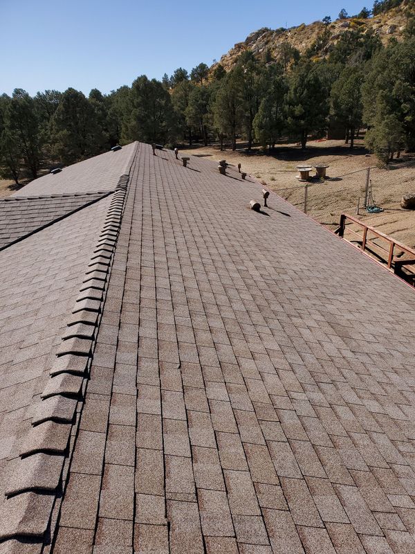 A roof with a lot of shingles and trees in the background