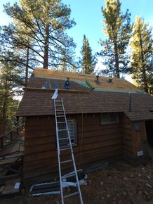 A ladder is attached to the roof of a log cabin