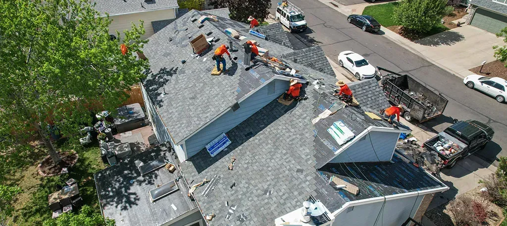 A group of people are working on the roof of a house.