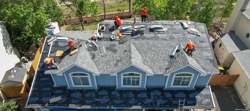 A group of people are working on the roof of a house.