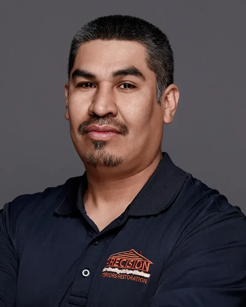 A man with a beard and mustache is wearing a blue shirt with a logo on it.