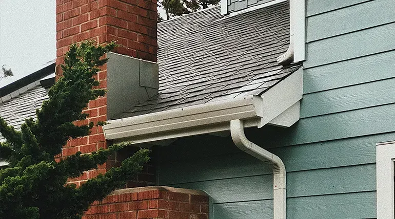 A house with a brick chimney and a gutter on the side of it.