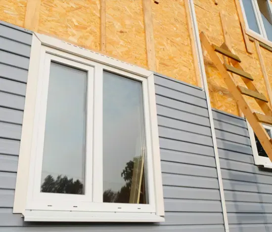 A house is being built with siding and windows.