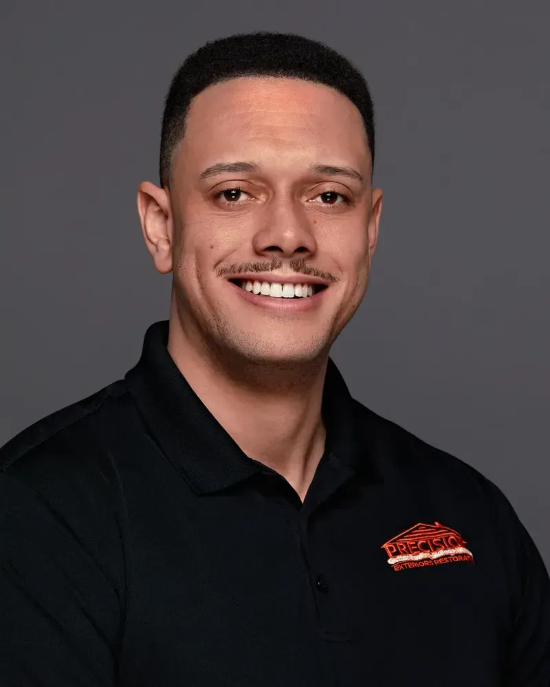 A man in a black polo shirt is smiling for the camera.