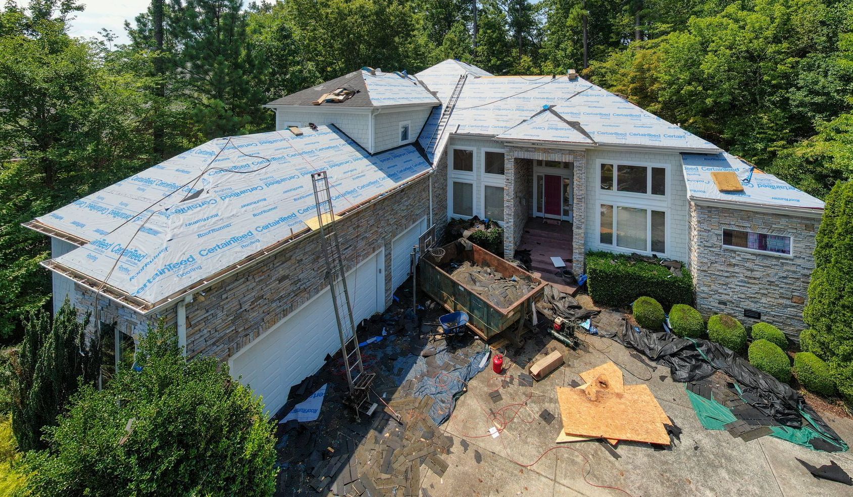 An aerial view of a large house with a roof being installed.