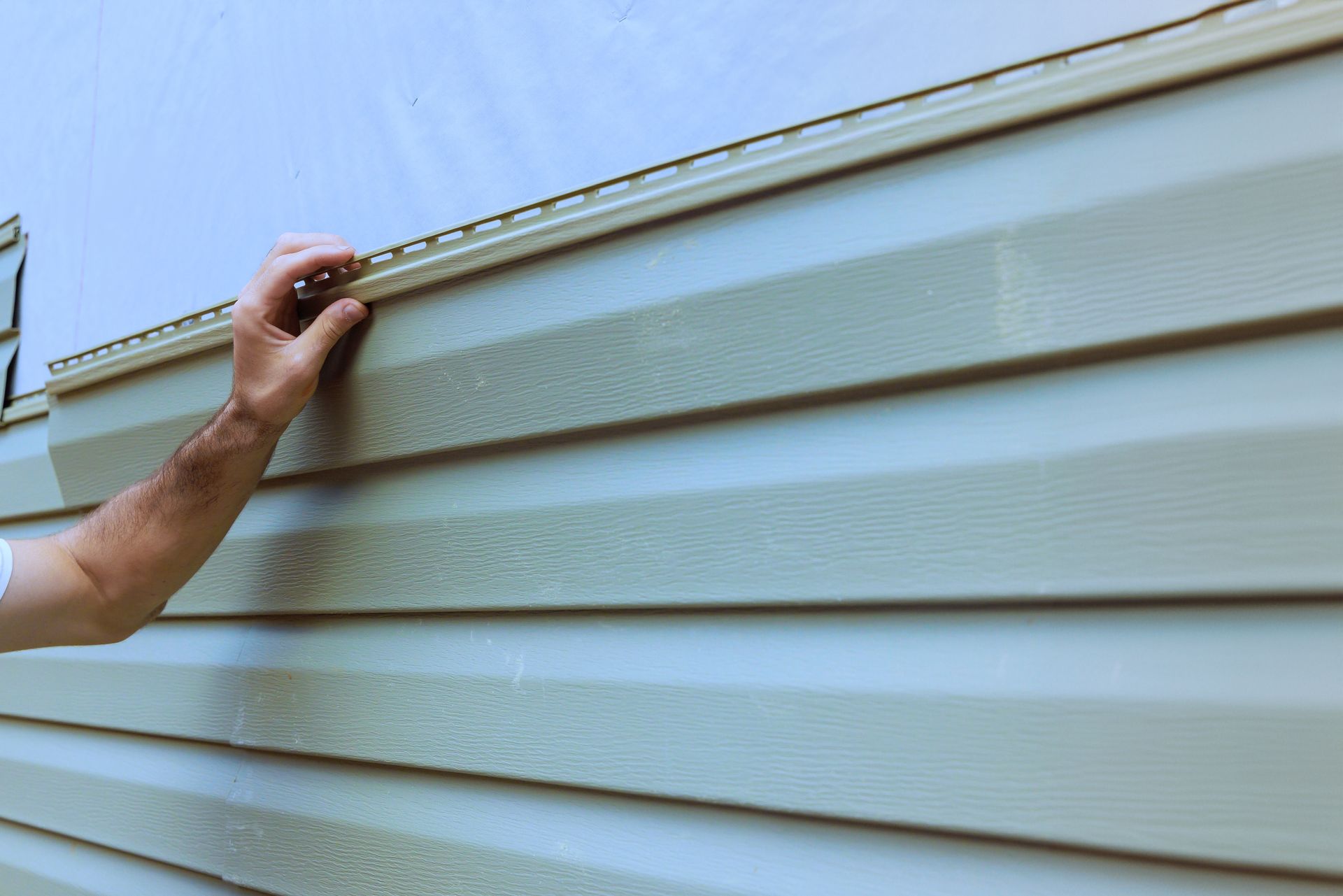 A man is installing siding on a house.