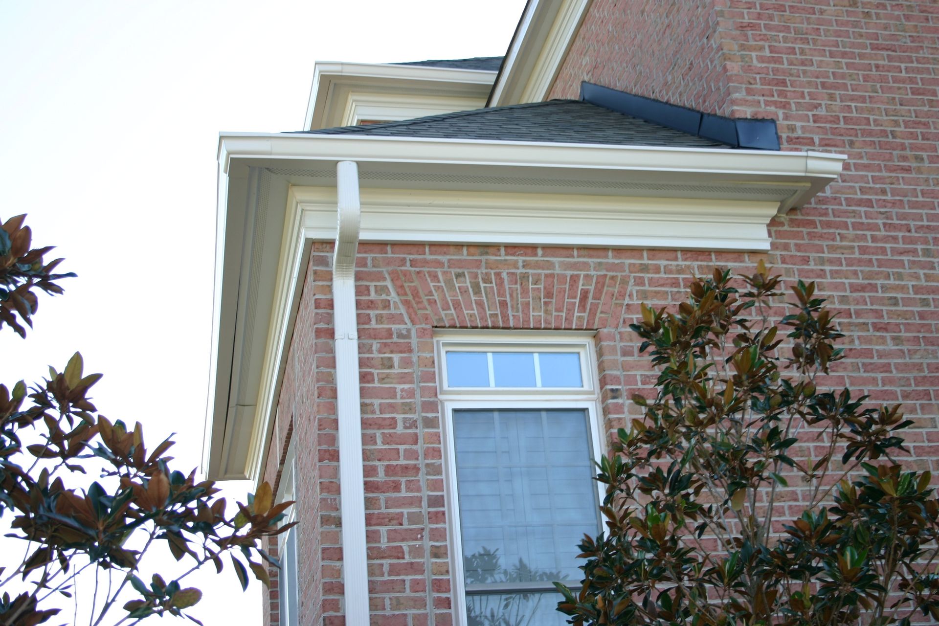 A brick house with a window and a tree in front of it