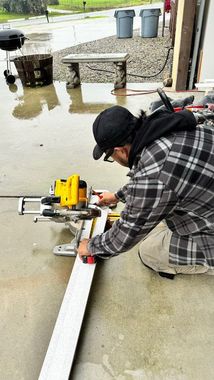 A man is cutting a piece of wood with a miter saw.