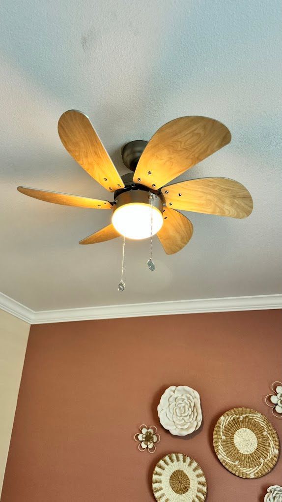 A ceiling fan is hanging from the ceiling in a room with plates on the wall.