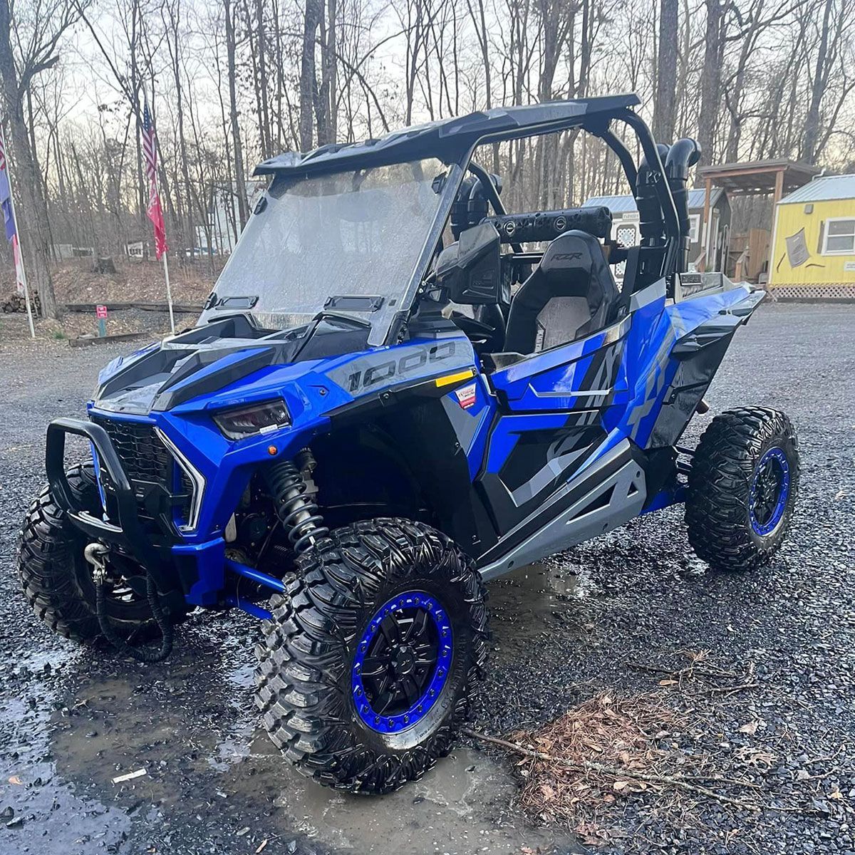 A blue and black atv is parked in a muddy area.