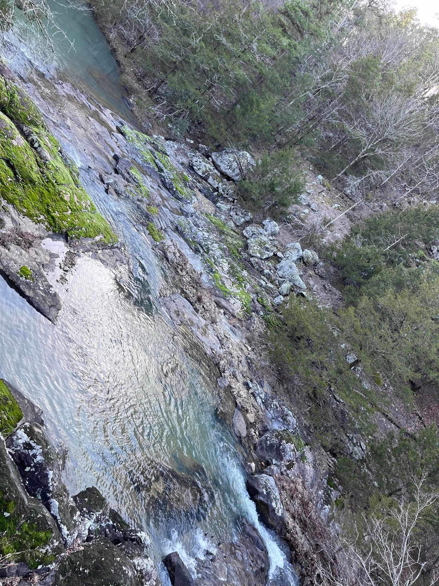 A waterfall is surrounded by rocks and trees in the middle of a forest.