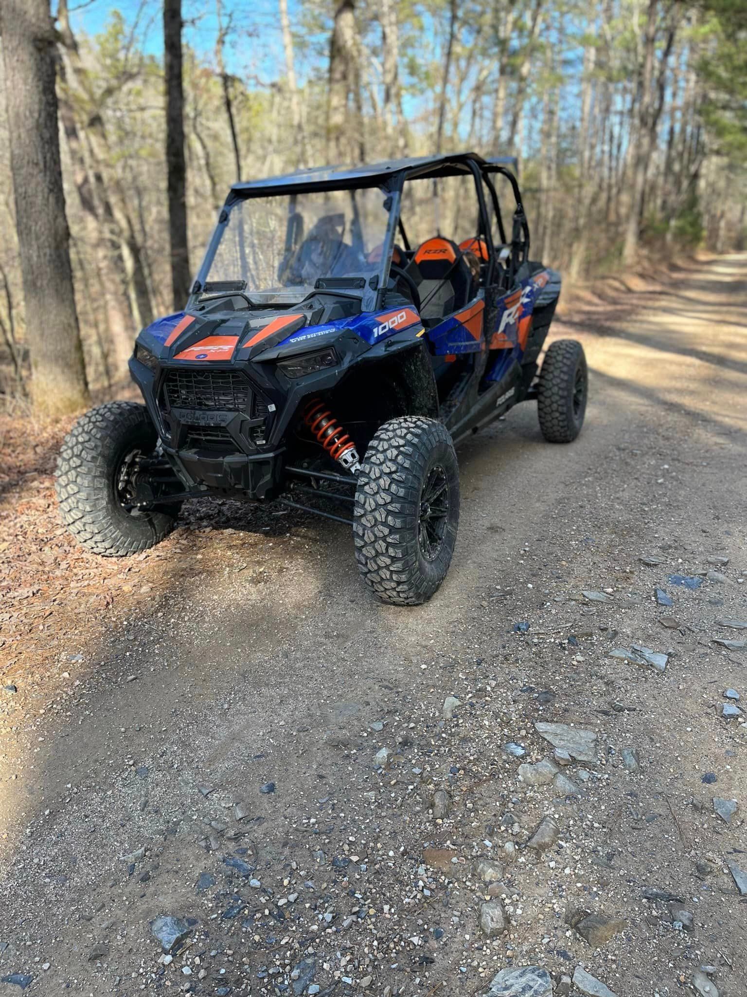 A blue and orange atv is parked on the side of a dirt road.
