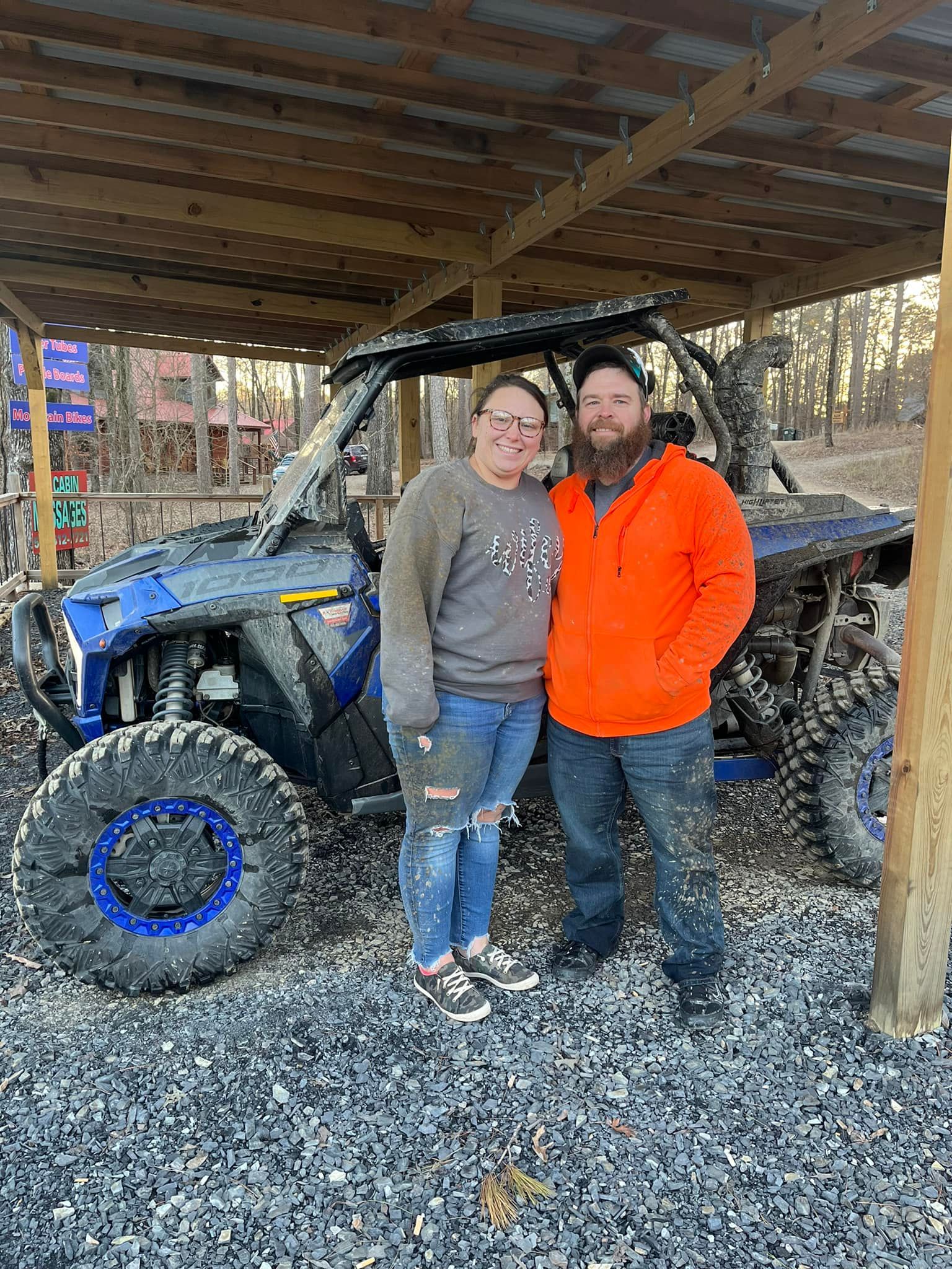 A man and a woman are standing in front of a atv.