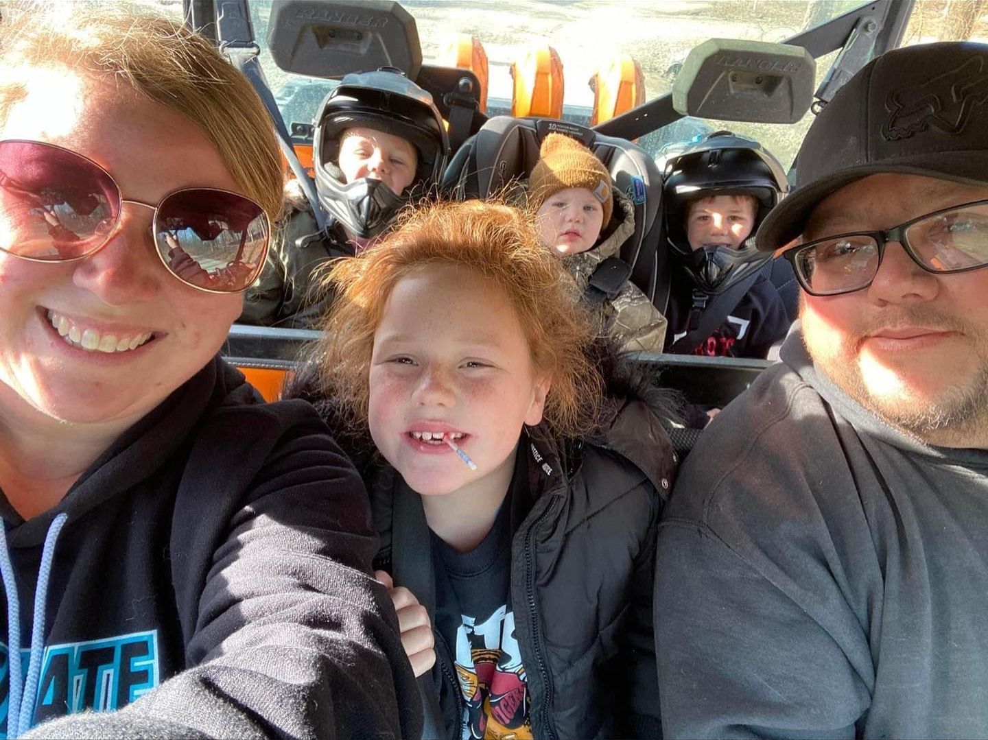 A family is taking a selfie in the back of a vehicle.