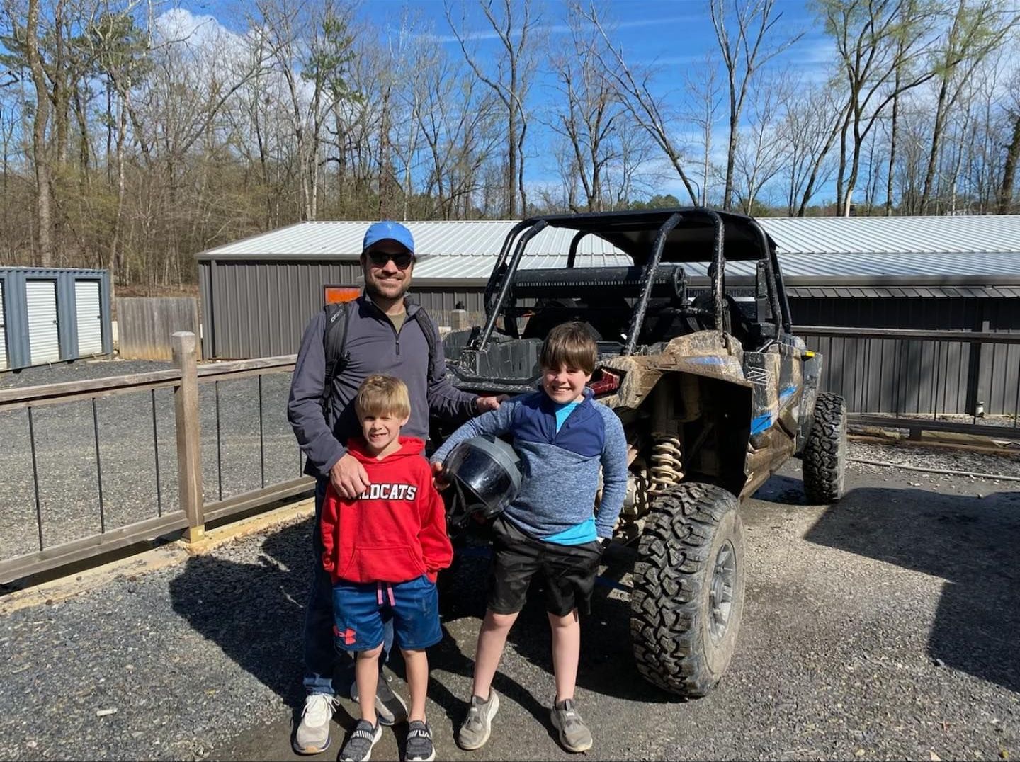A man and two young boys are standing in front of a atv.