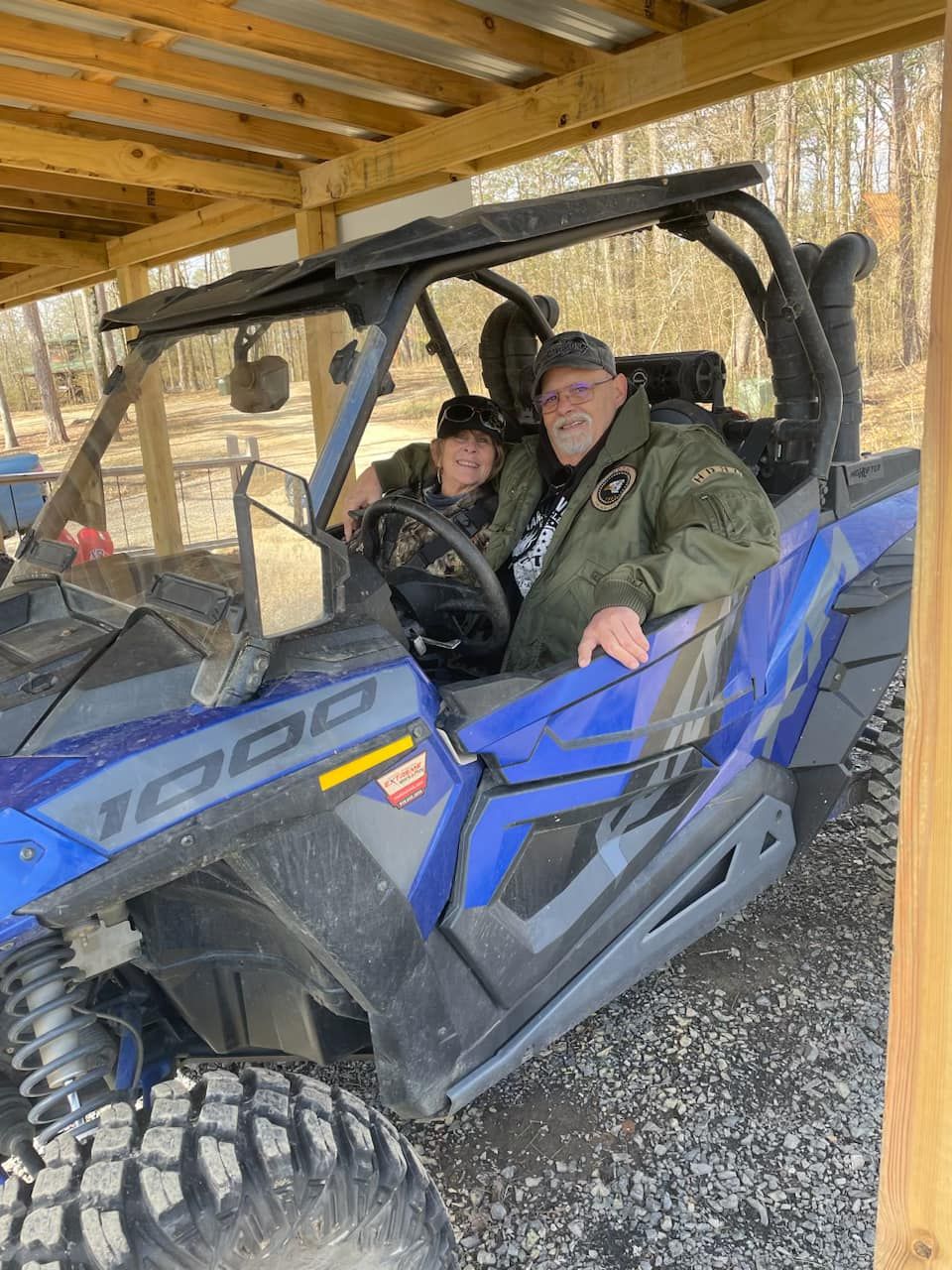 Two men are sitting in a blue atv.