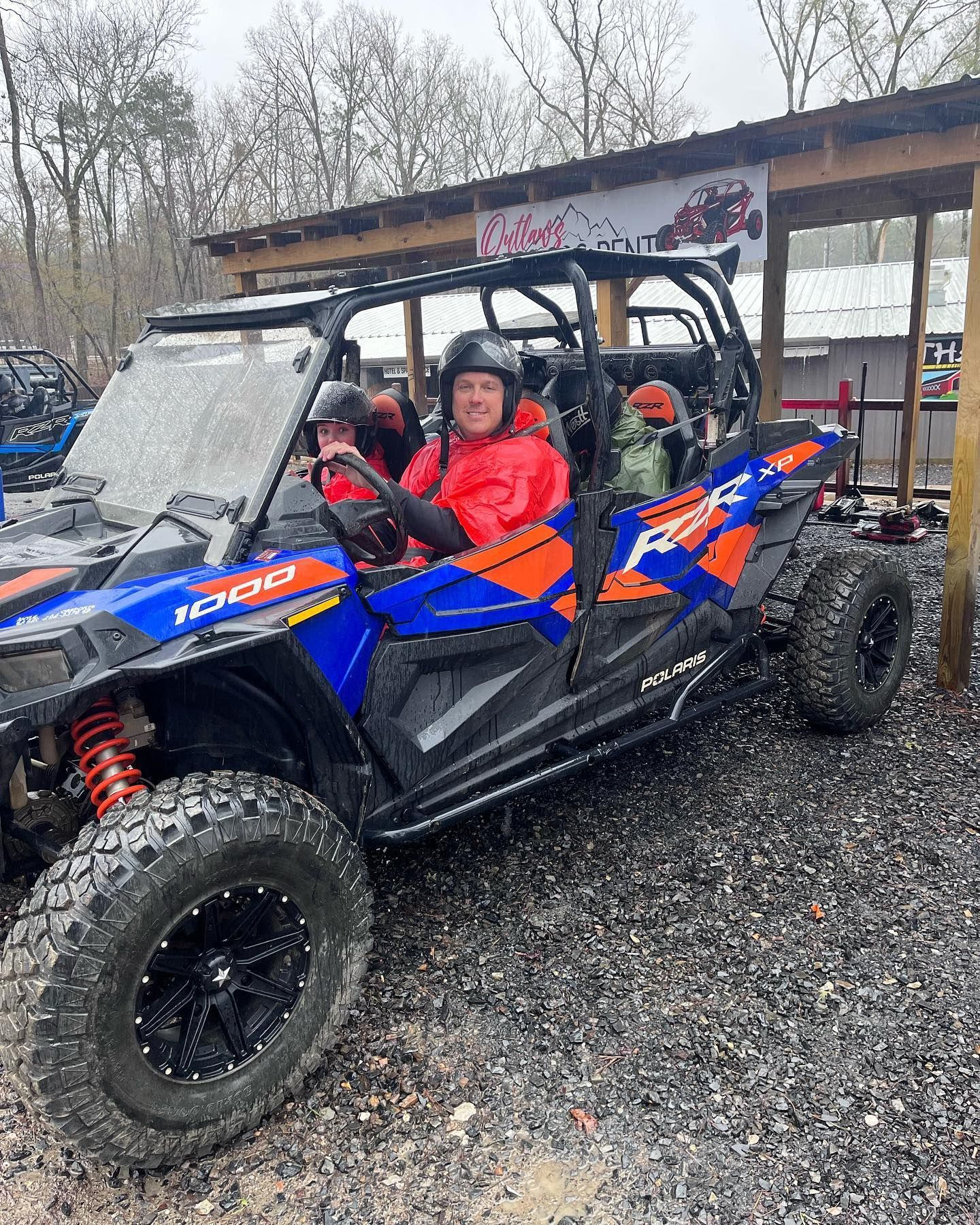 A man is sitting in a blue and orange atv.