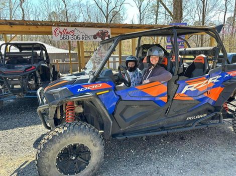 A woman is sitting in a blue and orange atv.