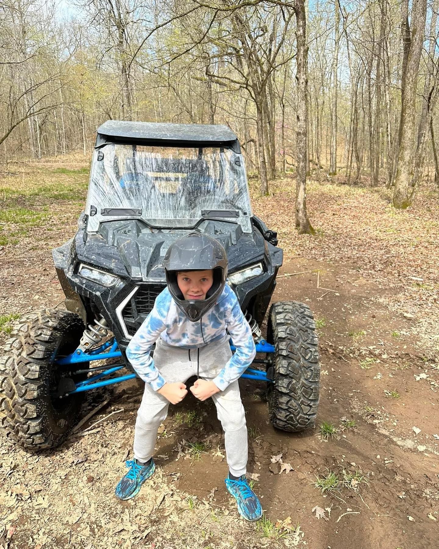 A young boy is sitting on a atv in the woods.