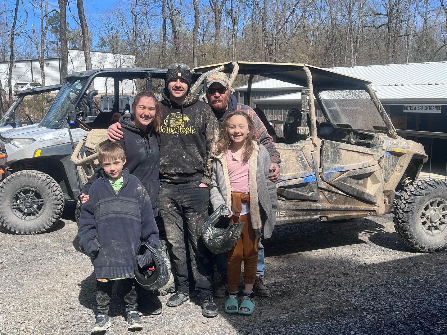 A family is posing for a picture in front of their atvs.