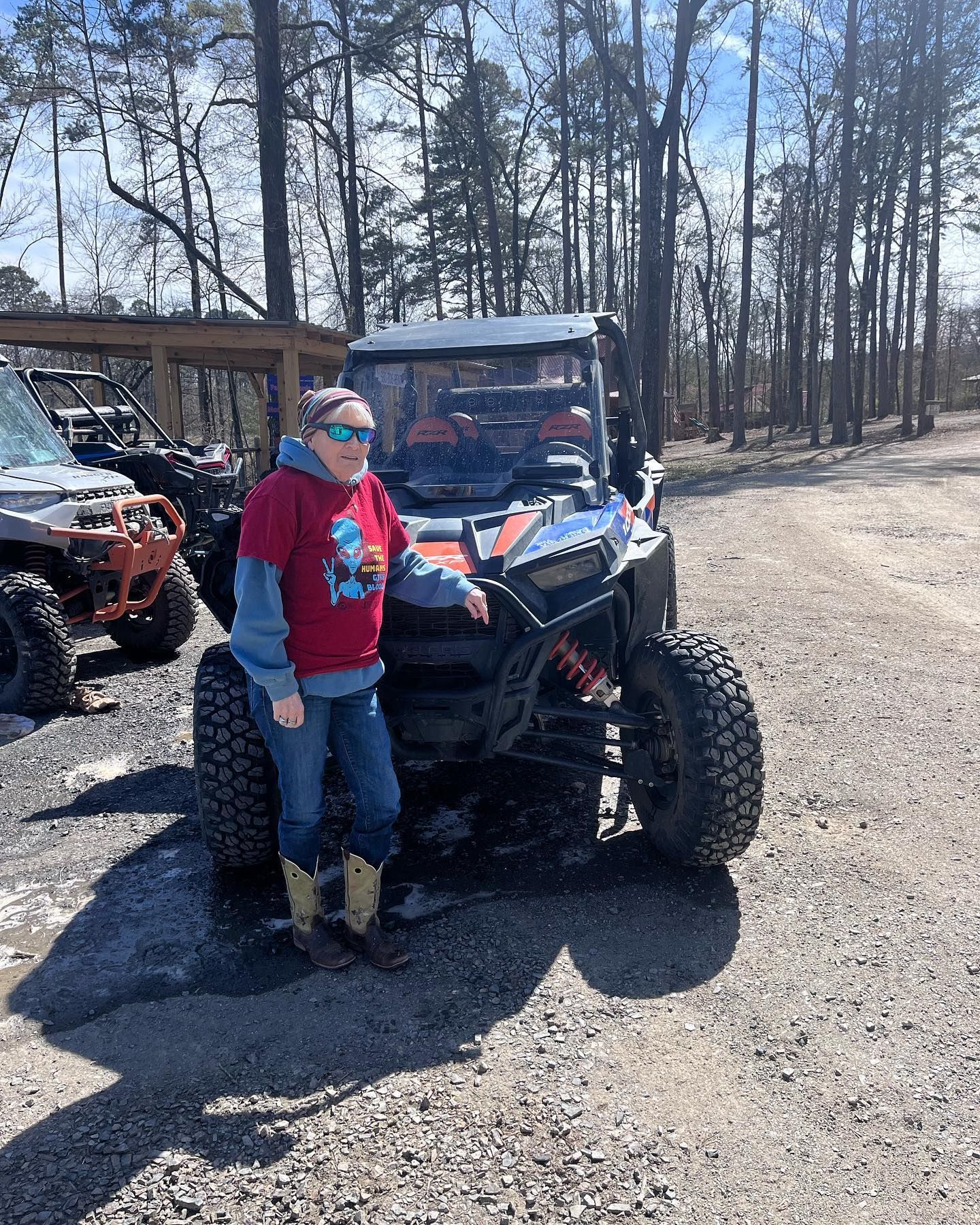 A woman is standing next to a atv in a parking lot.