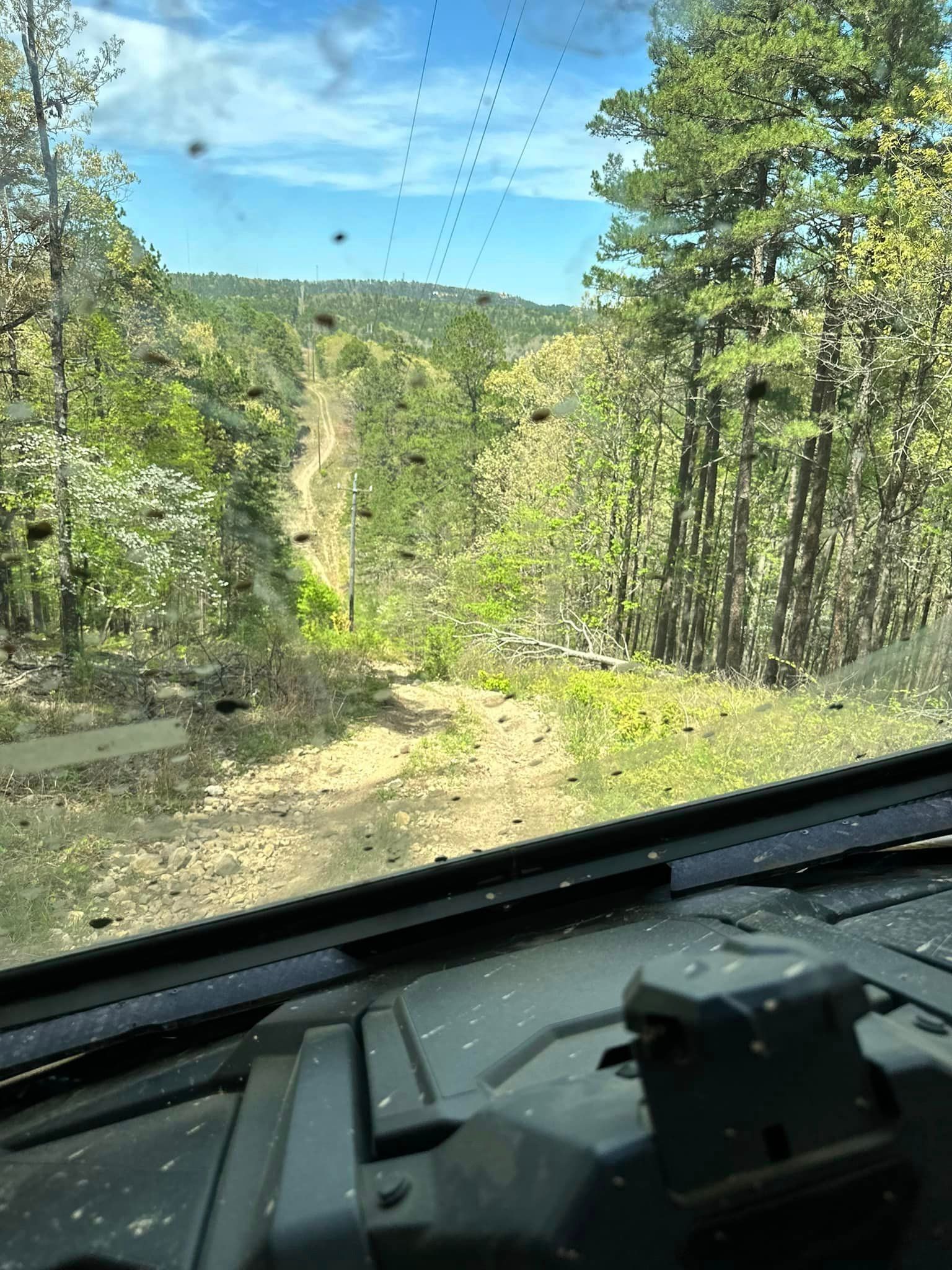 A view of a dirt road through a car windshield.