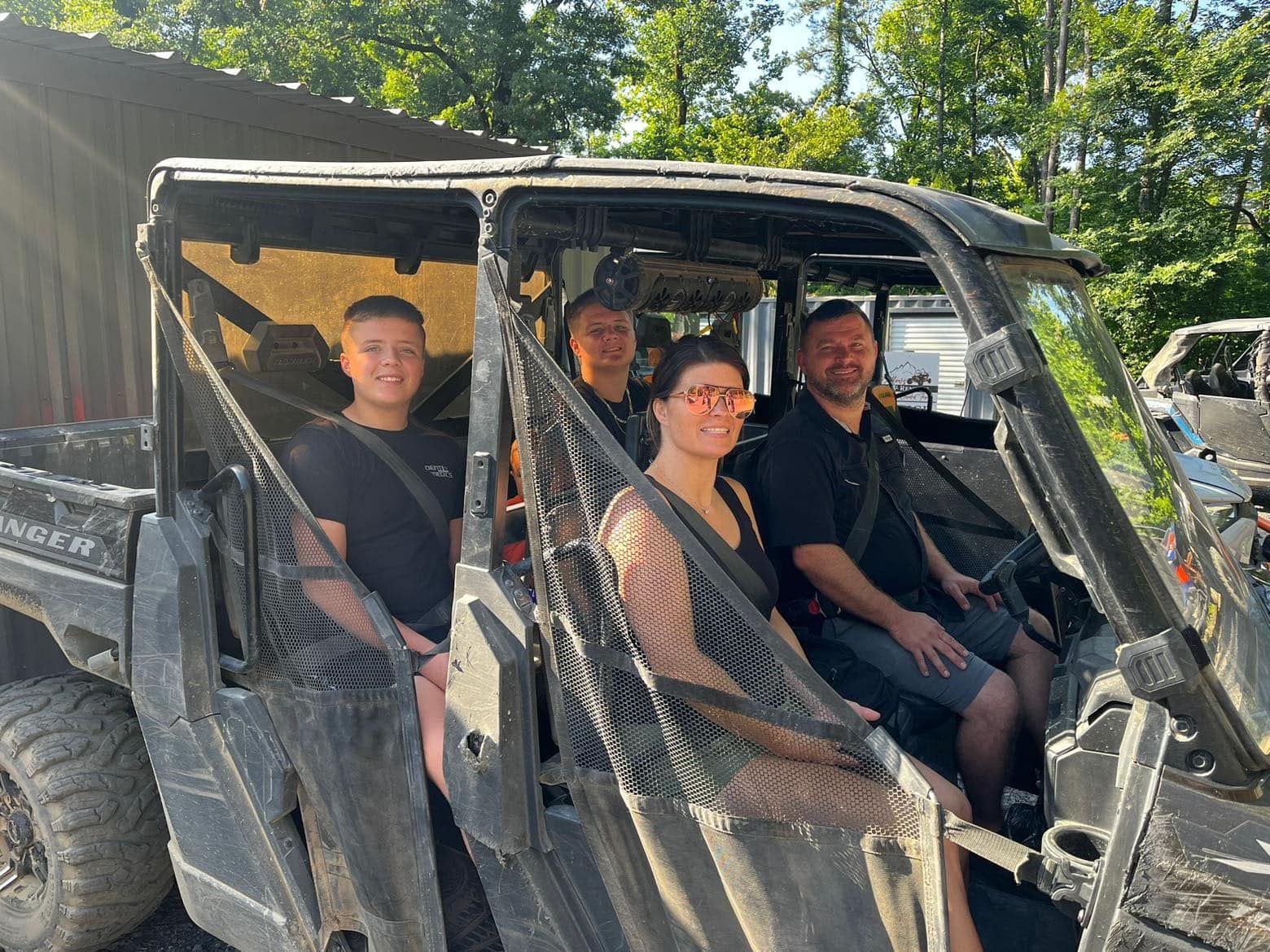A group of people are sitting in a muddy vehicle.