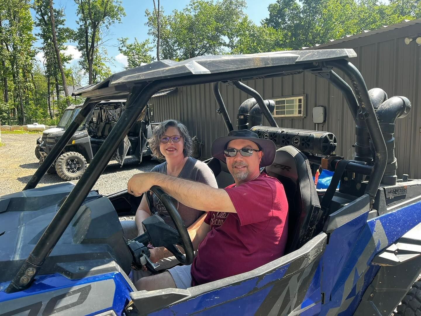 A man and a woman are sitting in a blue atv.