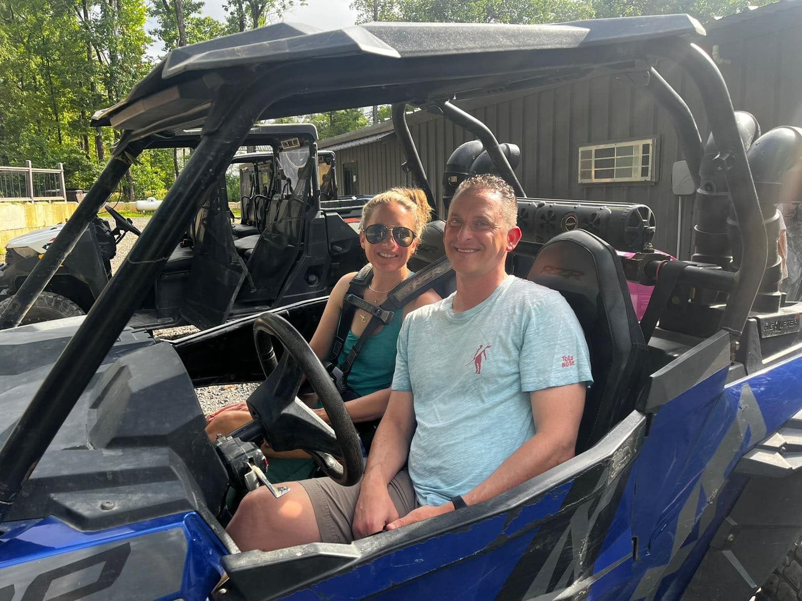 A man and a woman are sitting in a blue atv.