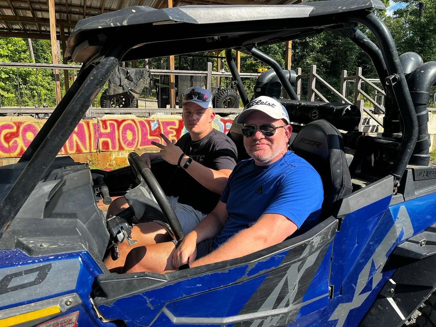 Two men are sitting in a blue atv.