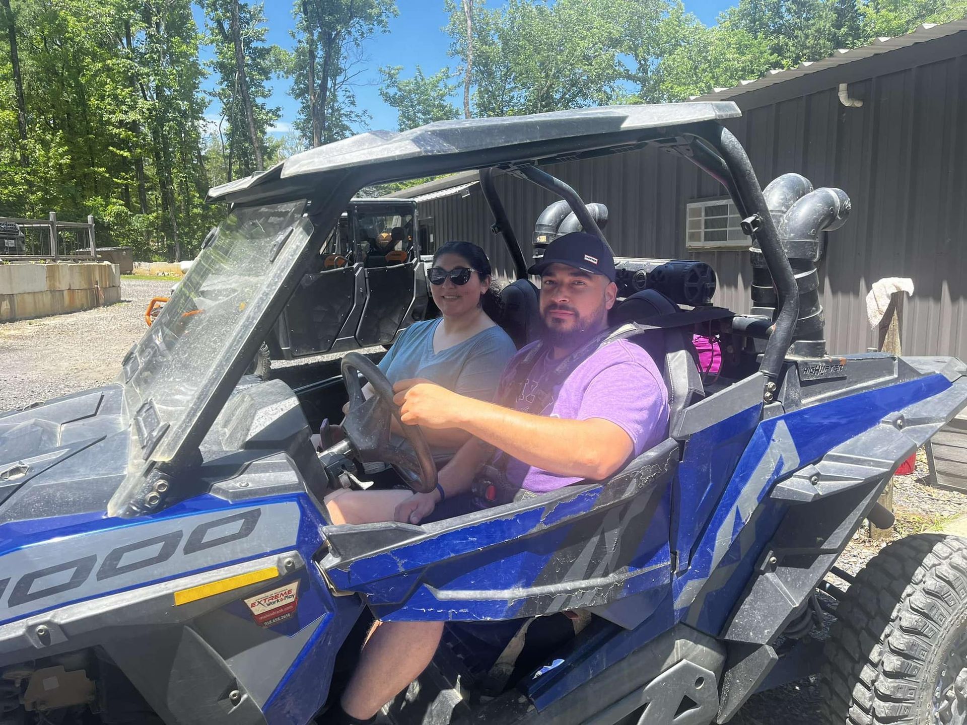 A man and a woman are sitting in a blue atv.