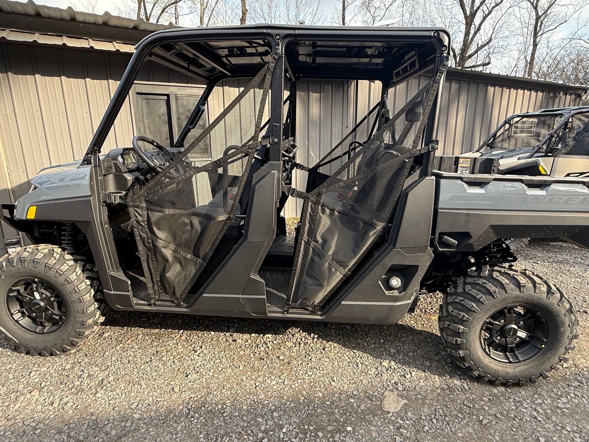 A polaris ranger xps is parked in a gravel lot in front of a building.