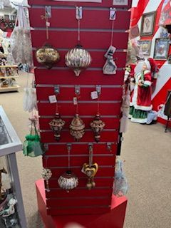 A red display rack holding various Christmas ornaments in a store.