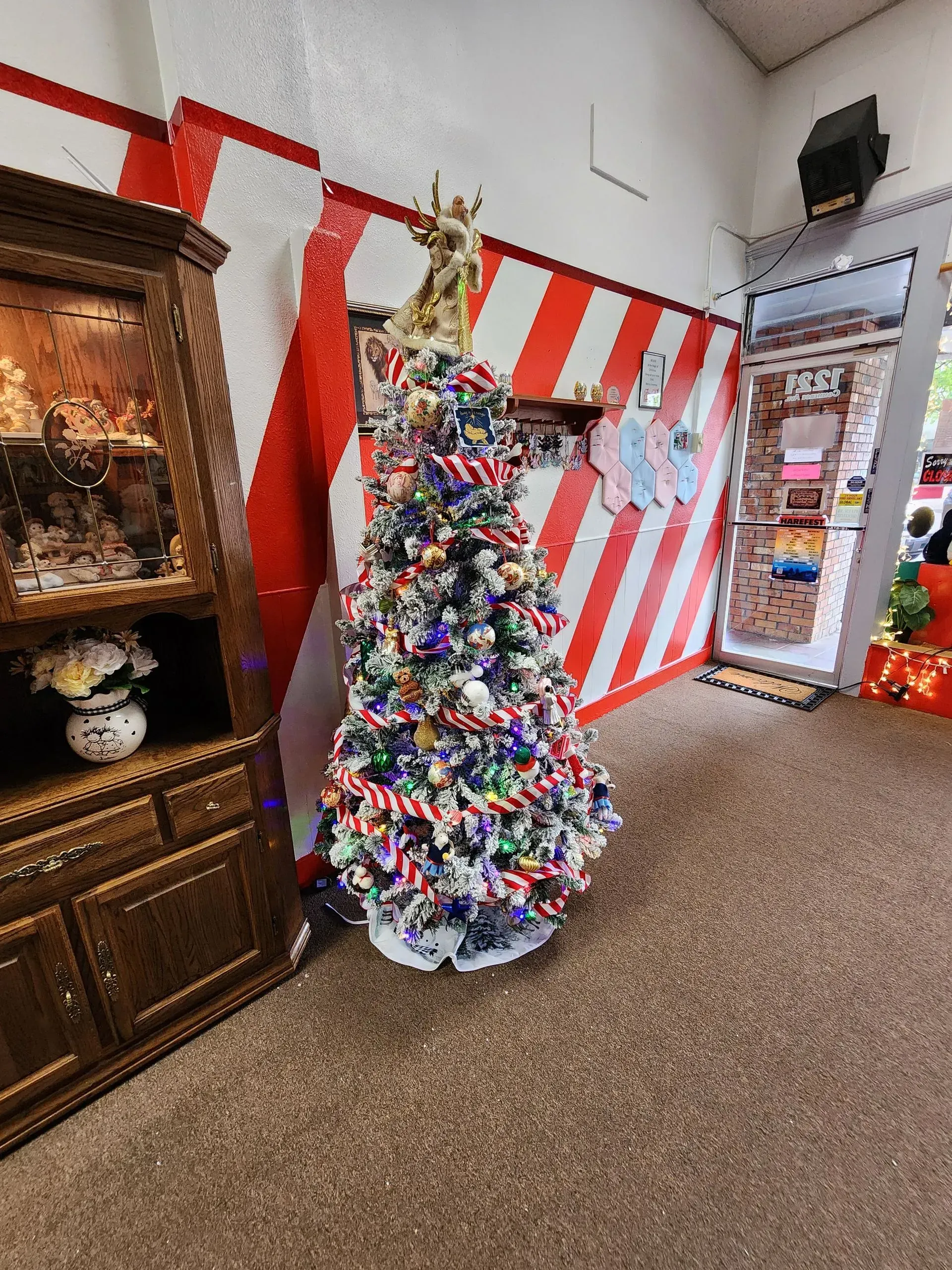 Christmas tree decorated with candy canes and lights, in a store with red and white striped walls.