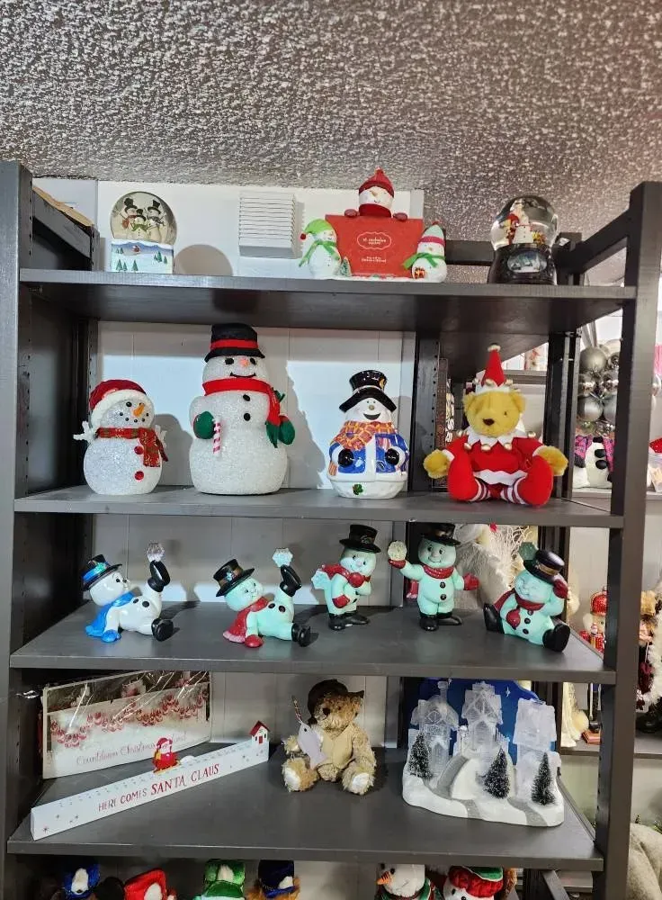 Shelf displaying various snowmen and Christmas decorations.