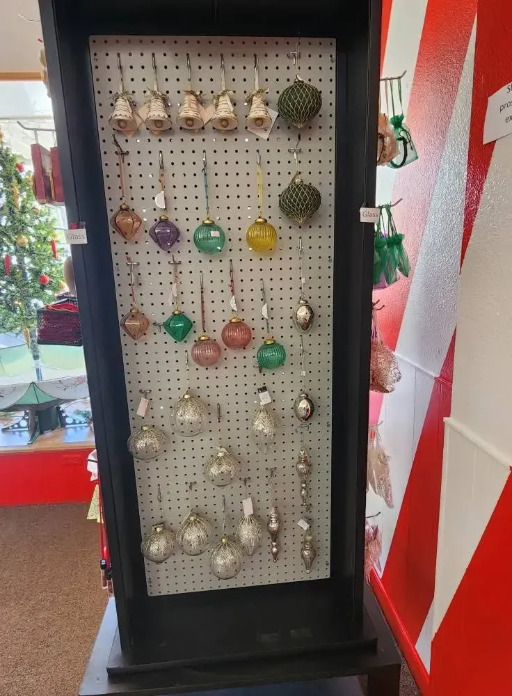 Display case with hanging Christmas ornaments of various colors and shapes.